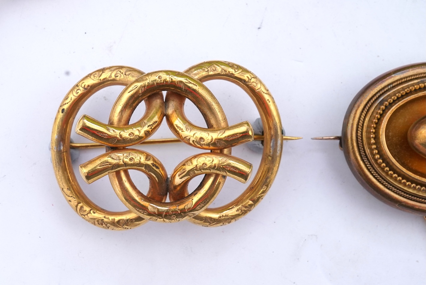 A group of gilt metal/pinchbeck jewels, 19th and early 20th century, comprising: a brooch of knotted design; two gate bracelets; a fancy link bracelet; an open-faced pocket watch; two oval panel brooches, and two watch c